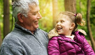 Grandad holding grandaughter while they both laugh Golden Leaves