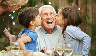 children happily kissing their grandfather