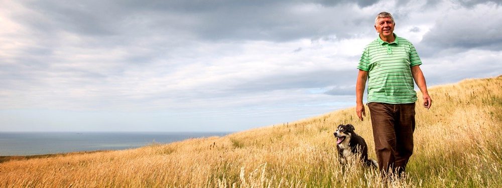 Man walking his dog in a field of long grass