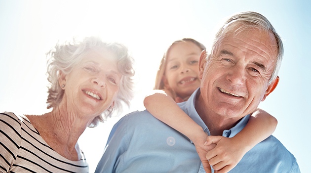 Grandparents looking happy, with granddad giving granddaughter a piggy back Golden Leaves Funeral Plans