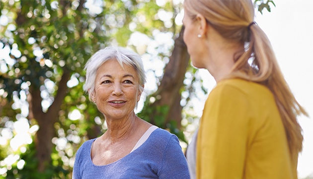 Senior woman chatting with another lady in a woodland