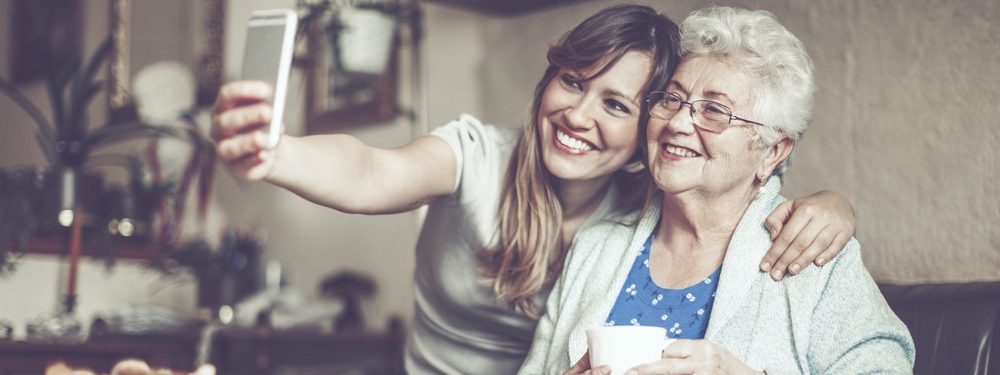 Senior lady and daughter take a smiling selfie together