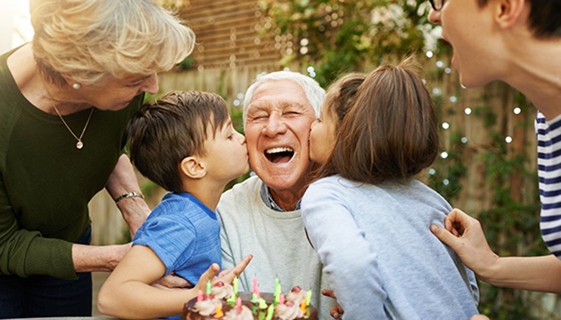 Grandfather being kissed on either cheek by two grandchildren