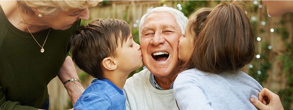 Grandfather being kissed on either cheek by two grandchildren