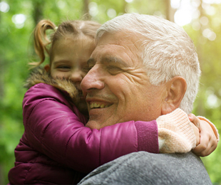 Grandfather smiling while carrying his grand daughter and hugging best over 50 funeral plan