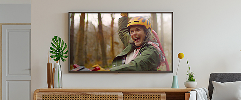 Tv screen in a living room showing woman celebrating while karting in the forest.