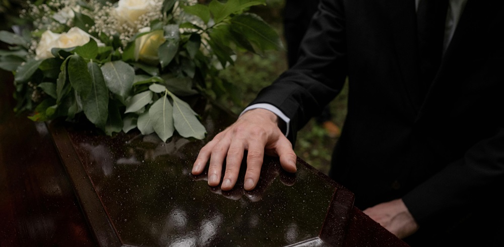 Man with hand on a coffin