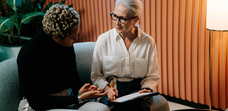 Two women sat on sofa looking at a clipboard