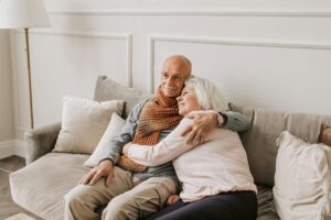 Elderly couple cuddling on sofa