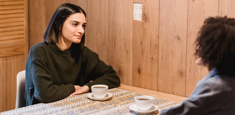 Best friends speaking at table with cups of coffee