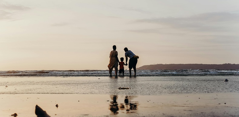 Photo of Three People Standing on Beach