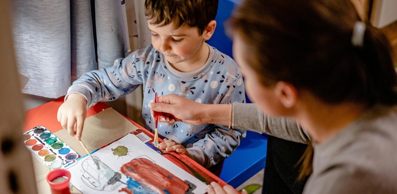 Mother painting picture with watercolour paints with her son