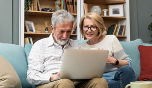 Older couple on the sofa researching together on a laptop
